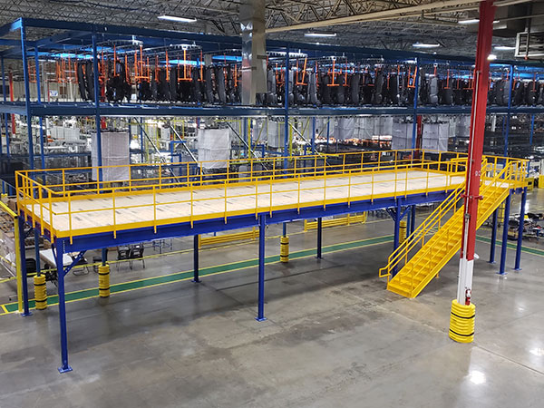 Blue mezzanine with yellow stairs and plywood deck in warehouse